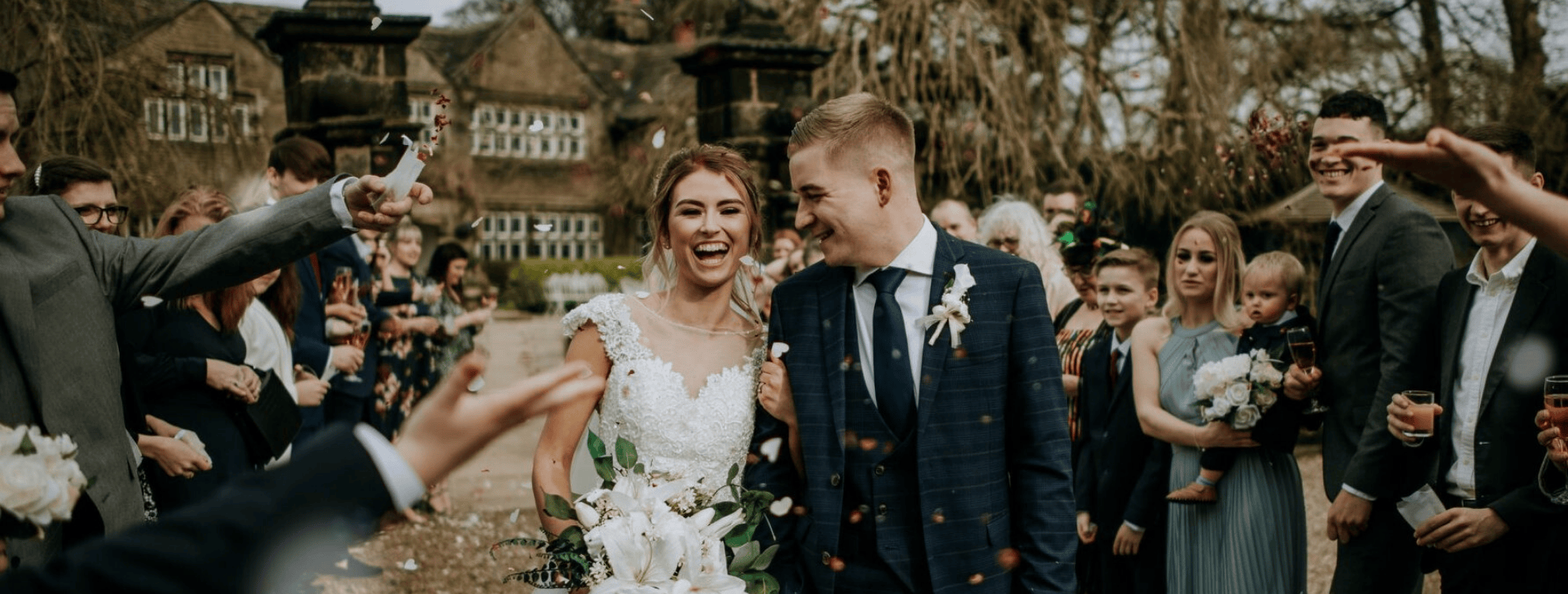 Newlywed couple walking through confetti shower at Holdsworth House, a historic wedding venue in Halifax.