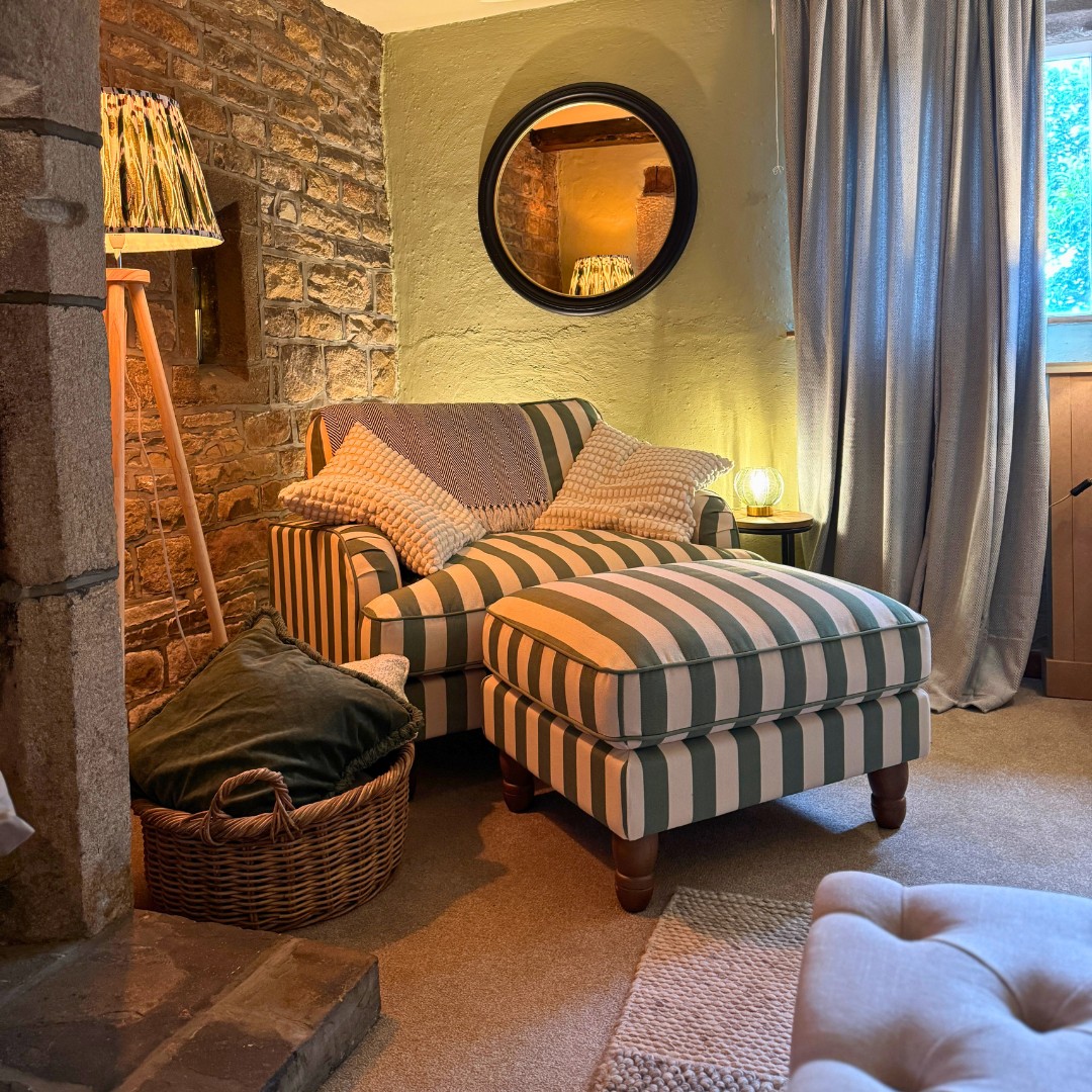 A striped chaise under the round mirror in the lounge