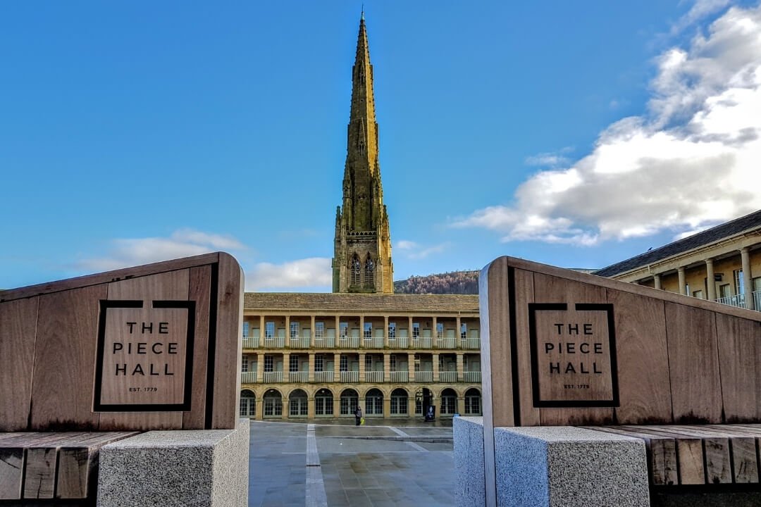 View of The Piece Hall courtyard with the spire of Halifax Minster in the background.