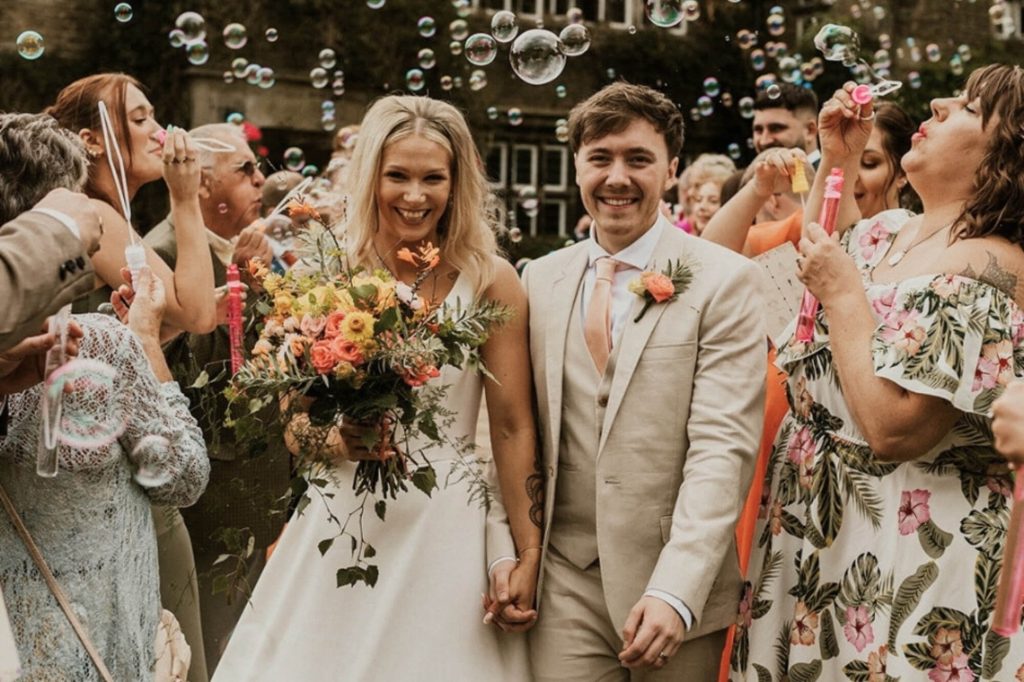 Wedding couple surrounded by guests throwing confetti at Holdsworth House.