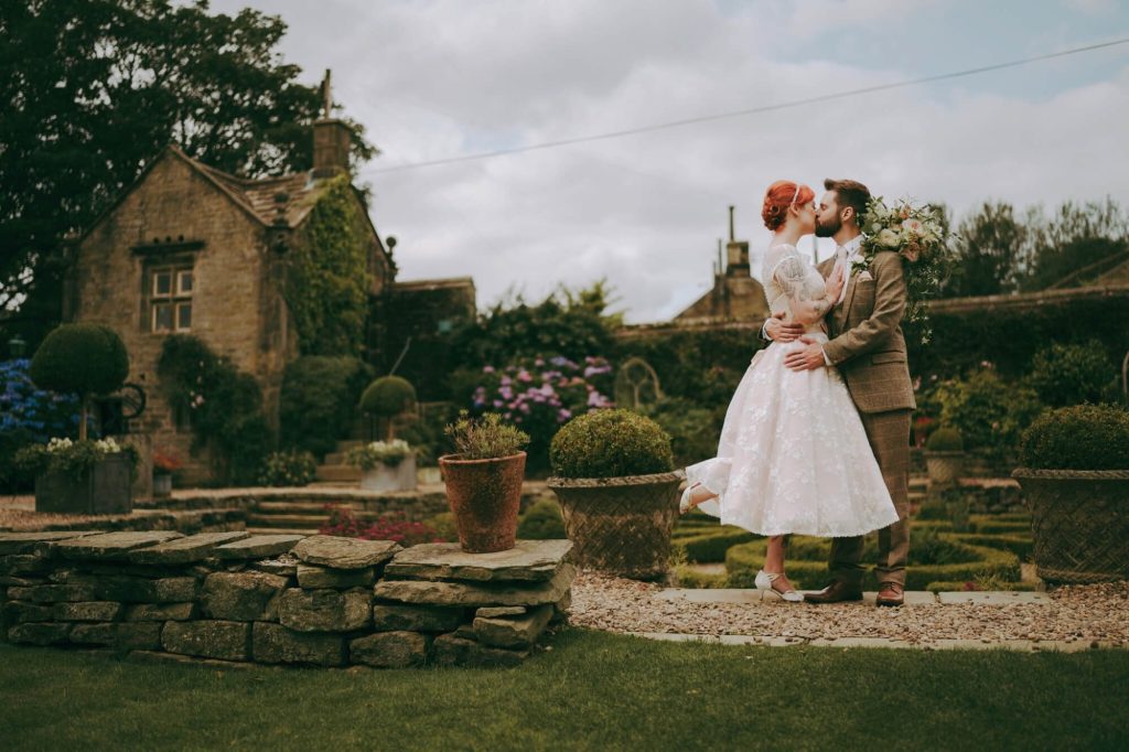 Wedding couple sharing a kiss in the gardens at Holdsworth House.
