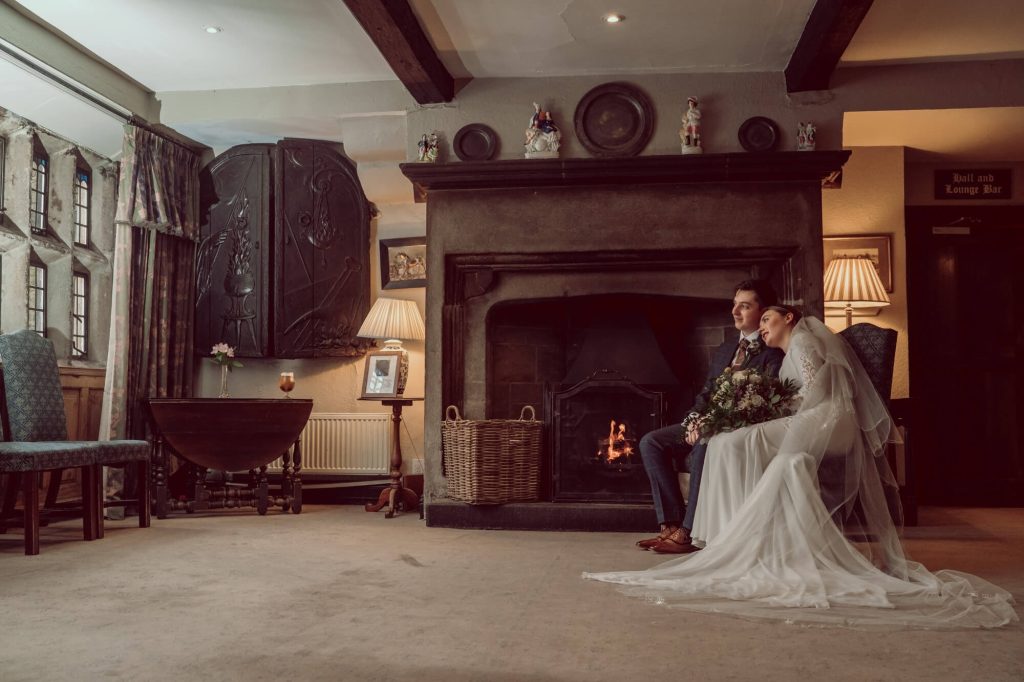 Wedding couple seated by the fireplace inside Holdsworth House.