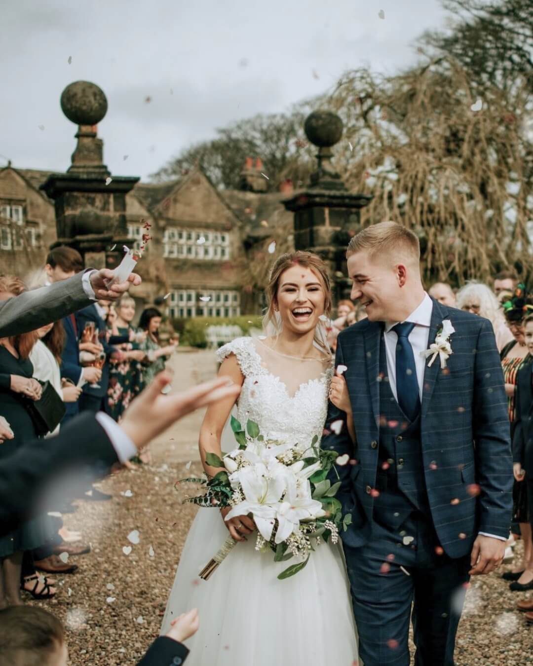 Newlyweds walking through confetti outside Holdsworth House wedding venue