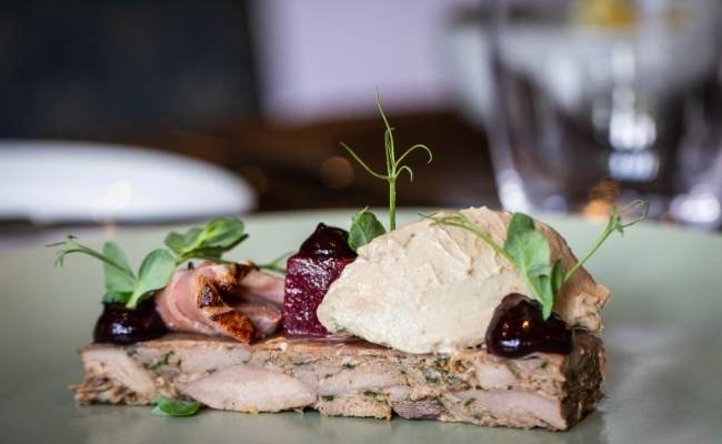 Seasonal lunch dish at featuring terrine with beetroot and herb garnish
