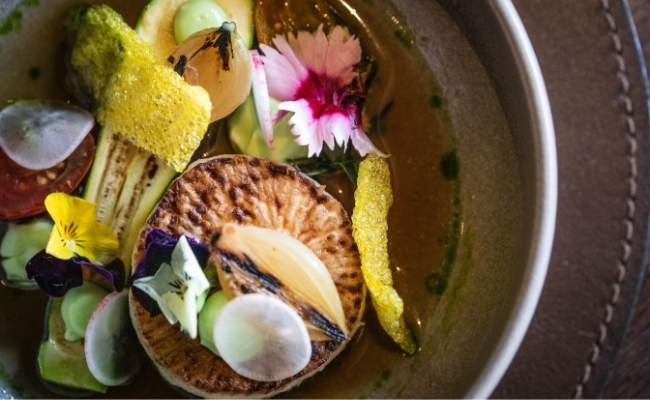 Seasonal tasting menu dish featuring scallop with garden herbs and edible flowers