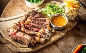 tomahawk steak served with fries, broccolini and sauce