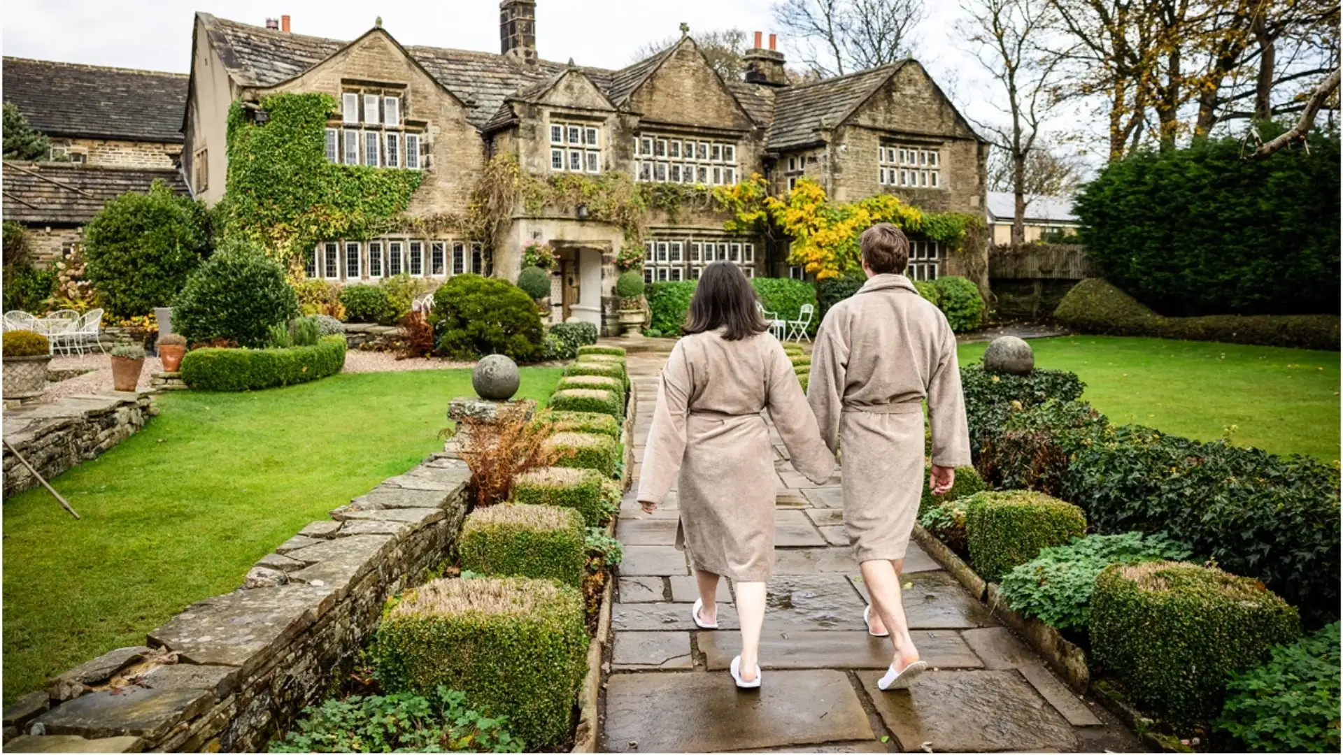 Two guests in robes walking the flagged path between The Farmhouse and Holdsworth House
