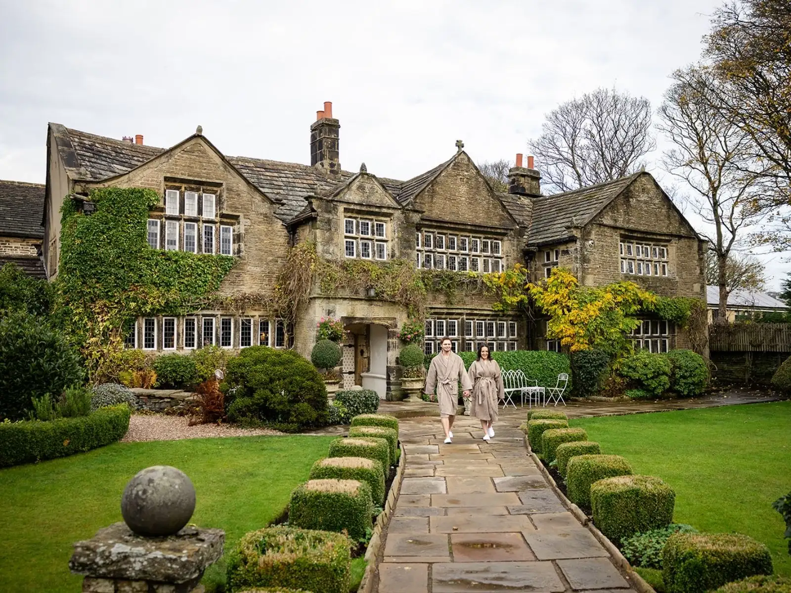 A couple in robes walking back to Holdsworth House along the flagged path