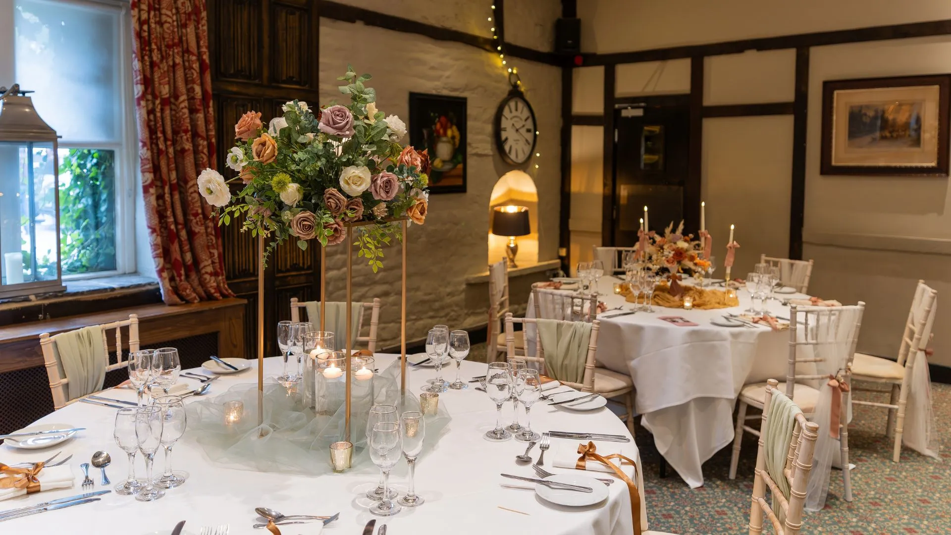 The Stuart Room at Holdsworth House laid with round tables and tall flowers for a celebration