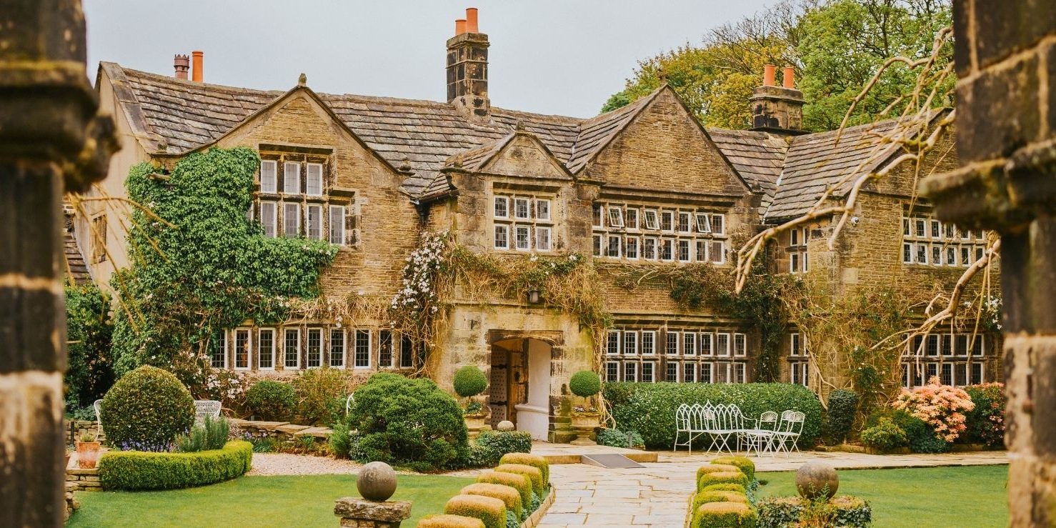 Front view of Holdsworth House, a historic Jacobean manor surrounded by manicured gardens